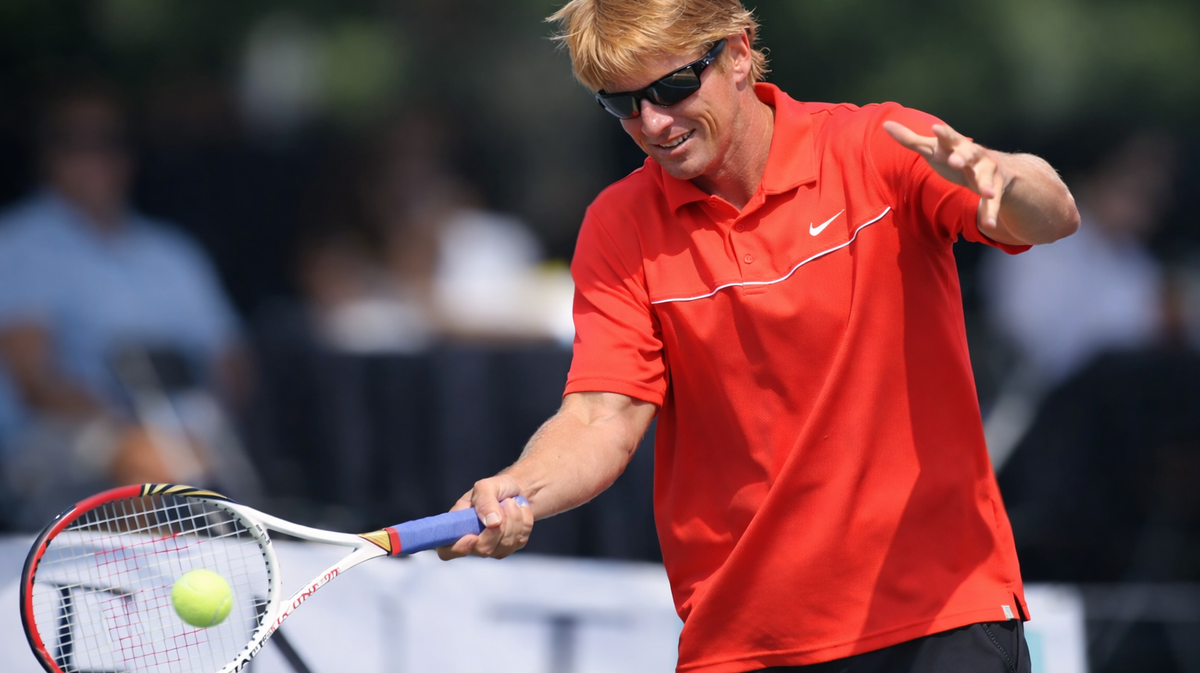 Bret Garnett wearing sunglasses and a red shirt while hitting a tennis ball