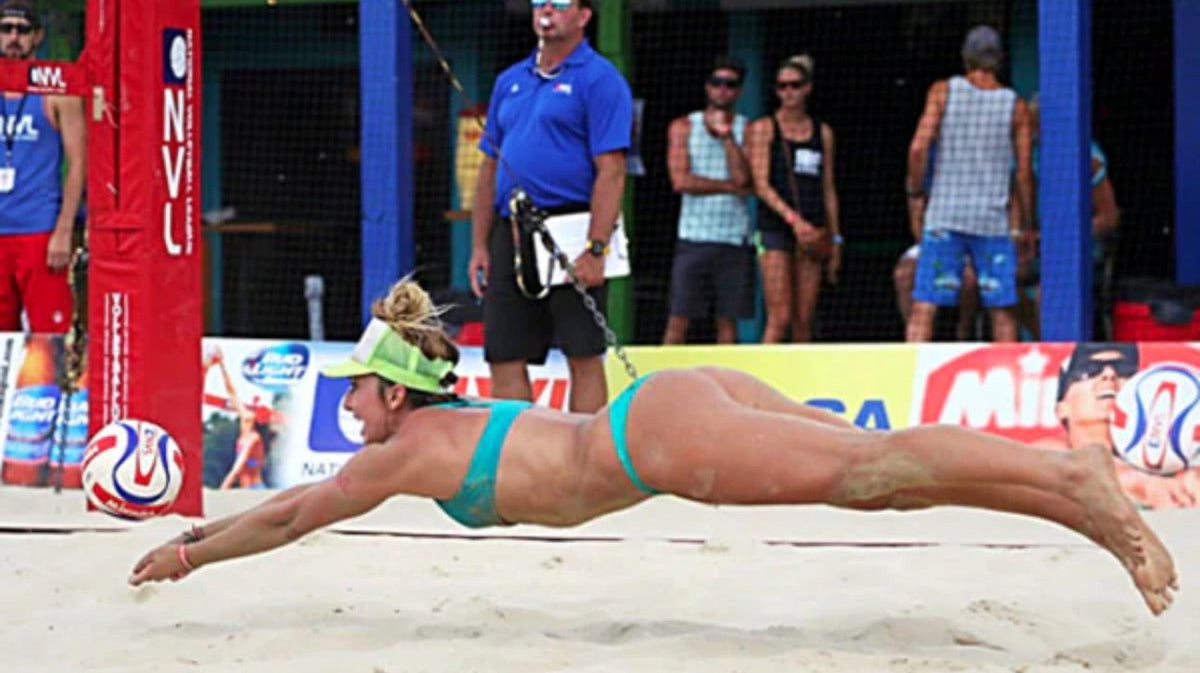 Kaley Melville diving for a beach volleyball on a sand court