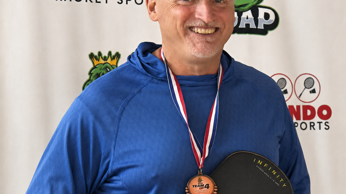 Paul Connifey wearing a medal and holding a black and yellow PBPRO paddle