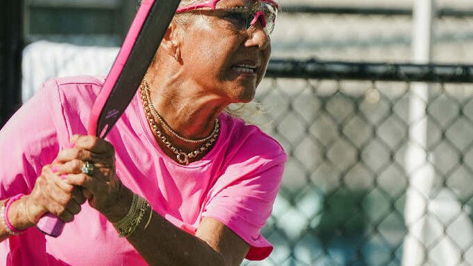 Anna Shirley wearing pink PBPRO Infinity eyewear while preparing a backhand