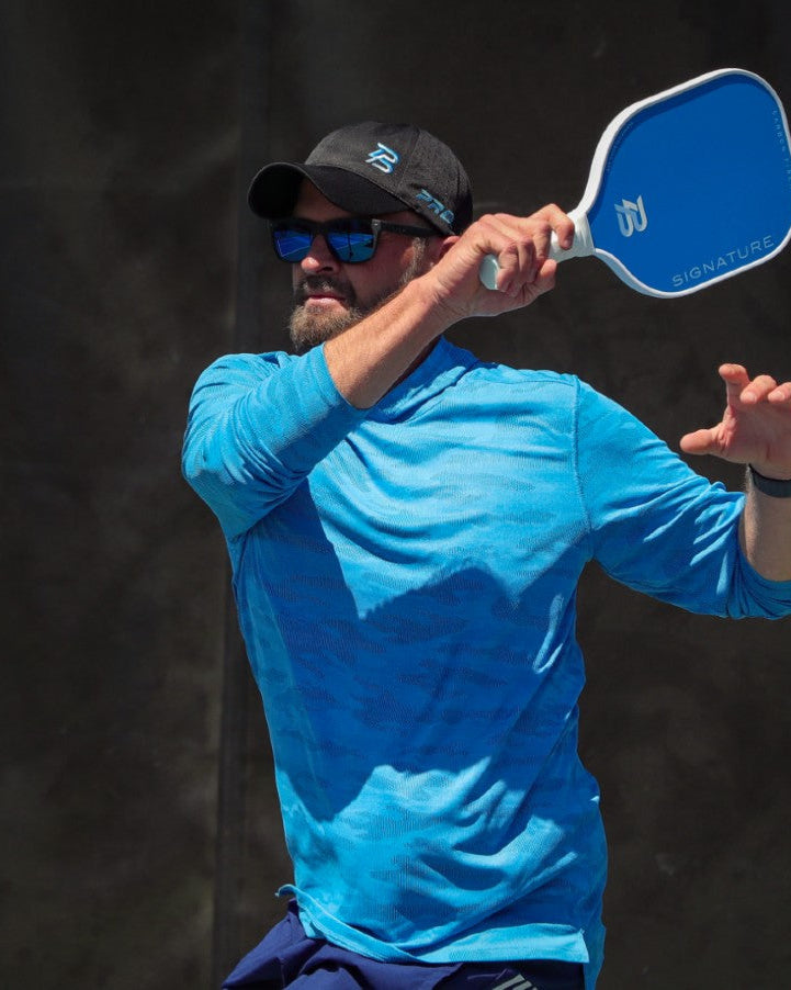 Pickleball player hitting a forehand with a PBPRO paddle on the court.