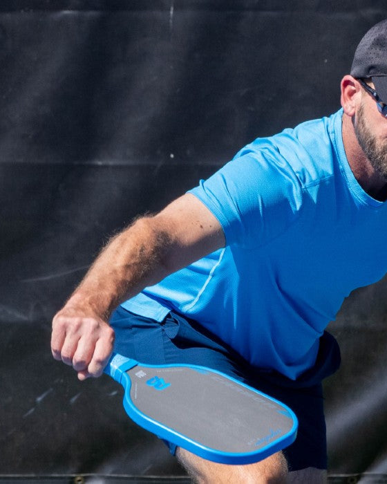 Player in a blue shirt hitting a ball with a blue PB Signature Plus paddle