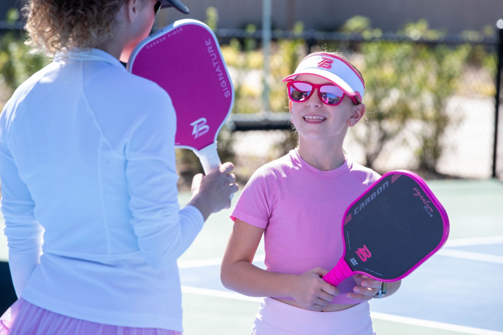 Junior pickleball players using PBPRO paddles during practice on an outdoor court