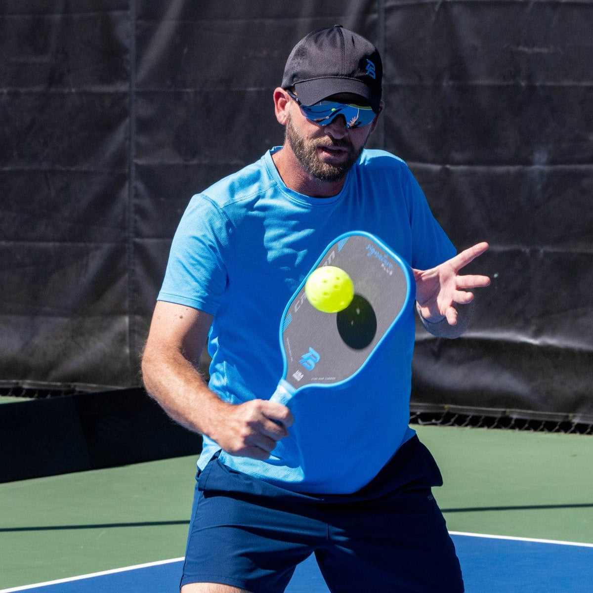 Blue PB Signature Plus 16mm T700 pickleball paddle, used by a player hitting a ball