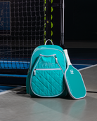 Mint PBPRO Signature pickleball backpack, standing beside a mint paddle on a court