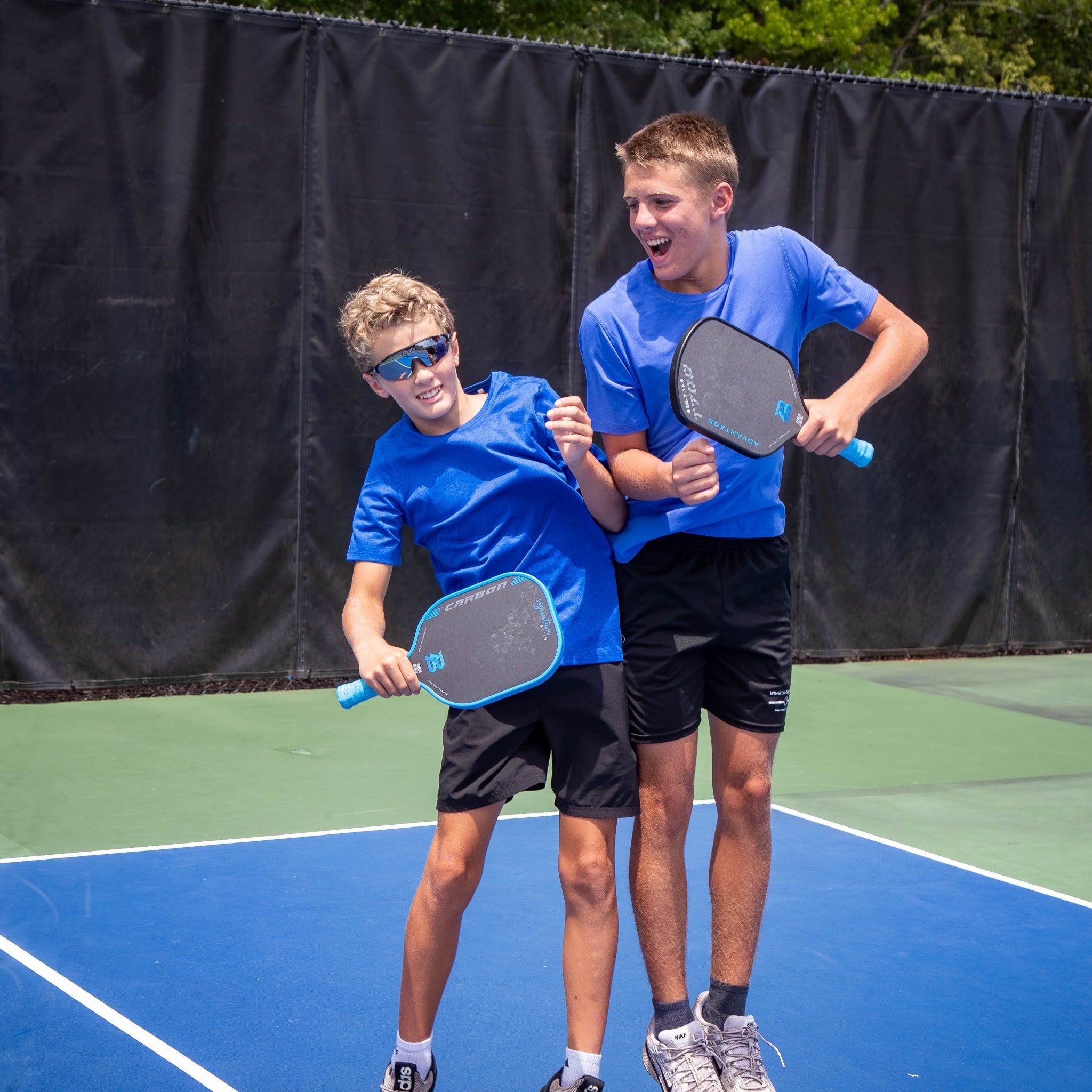 Two young players in blue with PBPRO blue pickleball paddles