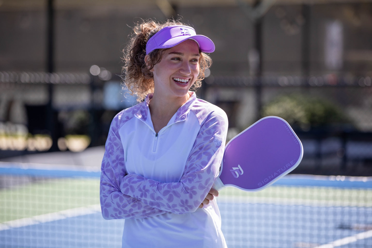 Player wearing a lavender visor with a lavender PBPRO Signature pickleball paddle